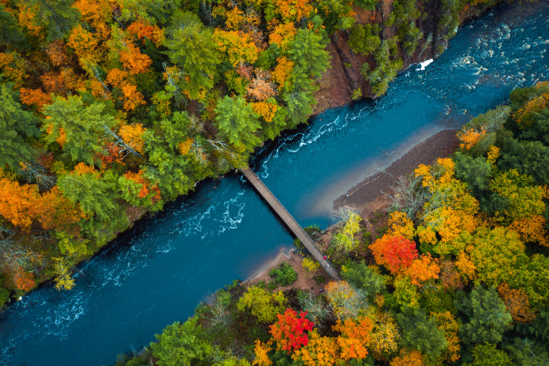Aerial shot of a river and a bridge surrounded by trees in Wisconsin