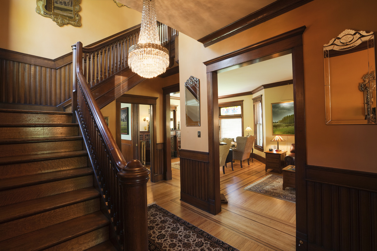 The interior foyer or entryway of an old restored Victorian style home, with oriental rugs and period furniture.